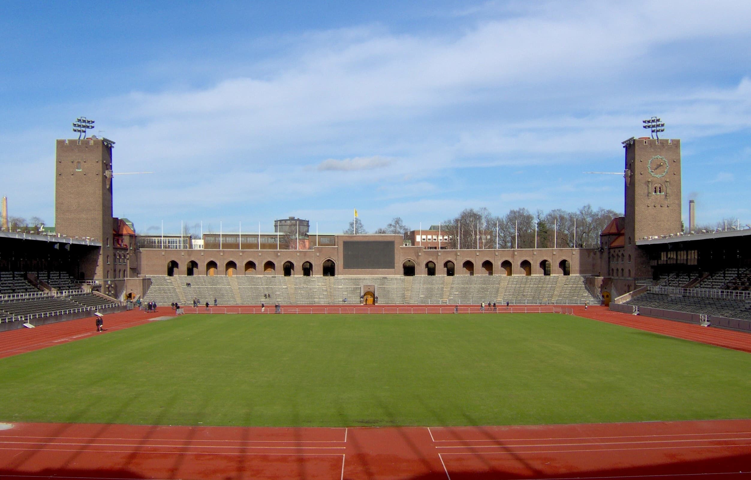 Stockholms Olympiastadion med tomma läktare och grön gräsmatta.