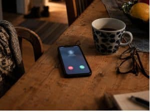 AI-bedrägerier ökar – mobiltelefon med inkommande samtal på ett köksbord