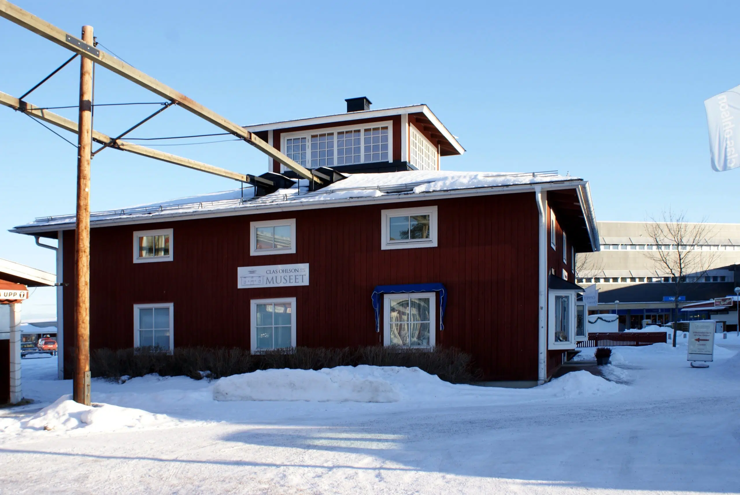 Byggnad med skylt för Clas Ohlson museet i Insjön, täckt av snö.