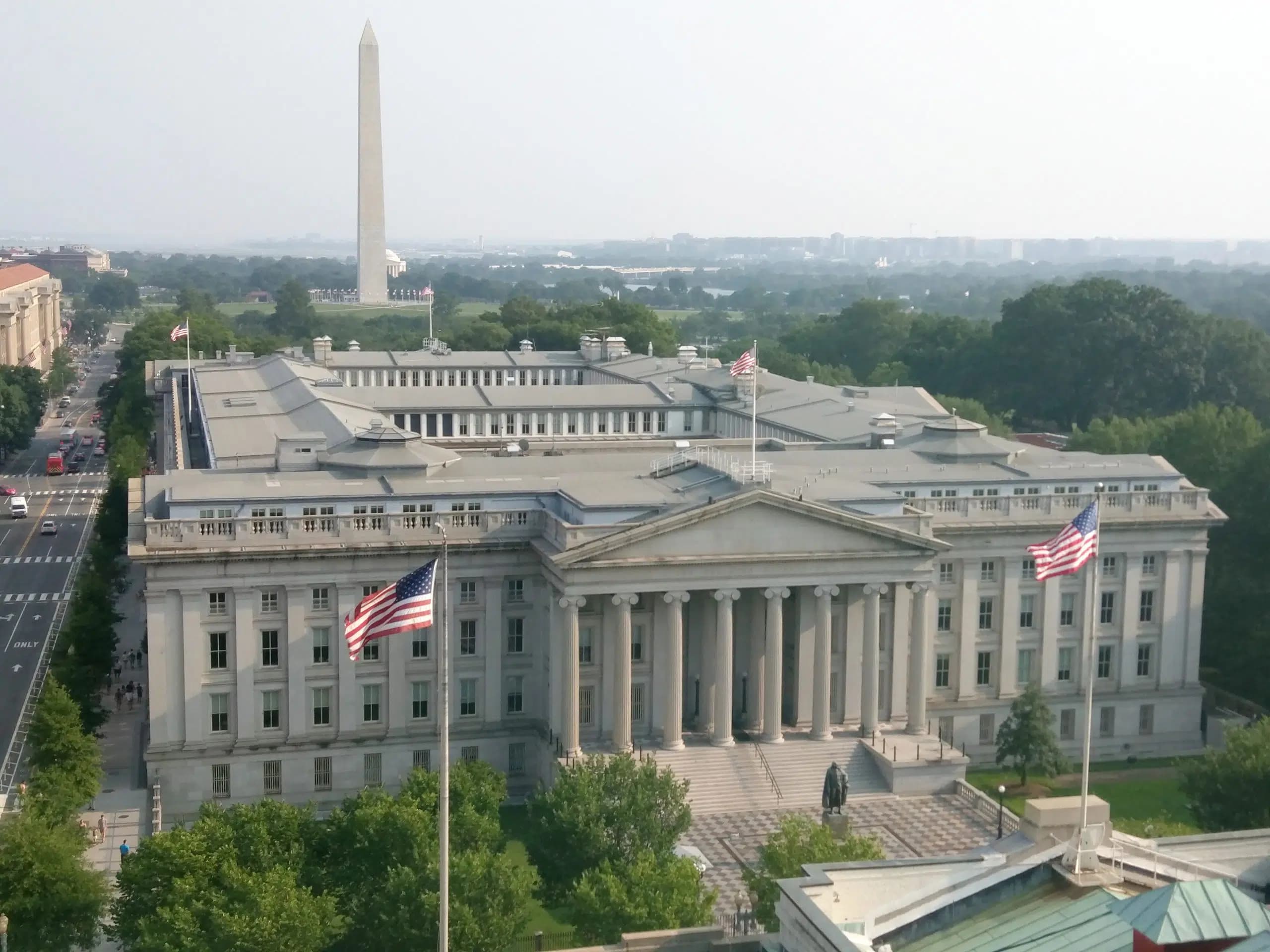 USA:s finansdepartementets byggnad med amerikanska flaggor i förgrunden.