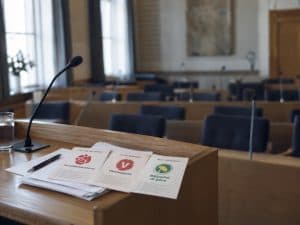 Vinster i välfärden – tomt kommunfullmäktige med valsedlar för S, V och MP på podiet