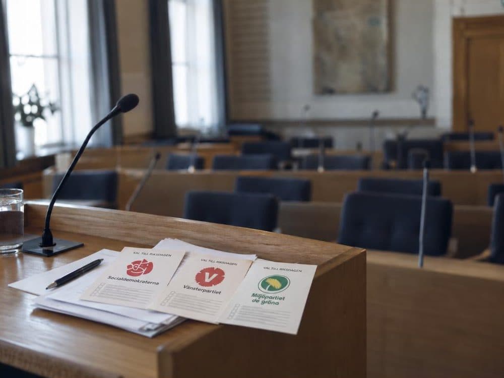 Vinster i välfärden – tomt kommunfullmäktige med valsedlar för S, V och MP på podiet
